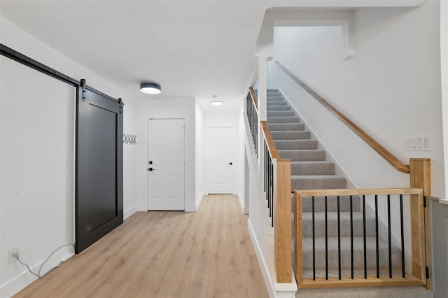 801 Edgefield Rd, Fort Worth, TX 76107 - hallway with a barn door, light wood-style flooring, stairs, and baseboards