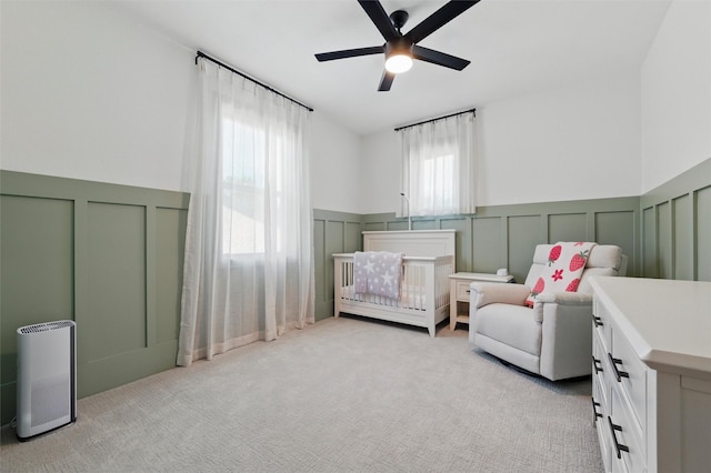 801 Edgefield Rd, Fort Worth, TX 76107 - bedroom with a decorative wall, wainscoting, light colored carpet, a crib, and a ceiling fan