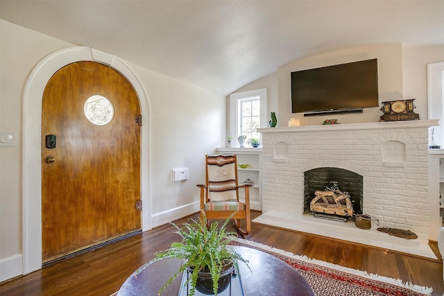 2133 Weatherbee St, Fort Worth, TX 76110 - entrance foyer featuring arched walkways, baseboards, wood finished floors, a fireplace, and vaulted ceiling