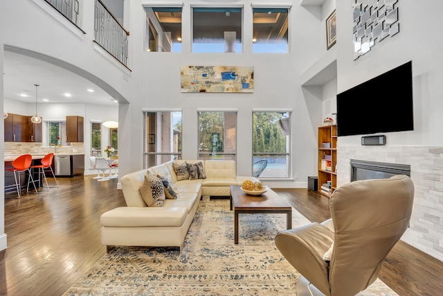 212 Saint Tropez Dr, Southlake, TX 76092 - living area featuring dark wood-style floors, a glass covered fireplace, a towering ceiling, healthy amount of natural light, and arched walkways