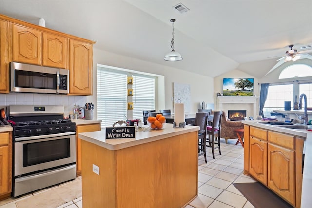 5000 Coral Creek Dr, Fort Worth, TX 76135 - kitchen featuring stainless steel appliances, a sink, light tile patterned floors, lofted ceiling, and a lit fireplace