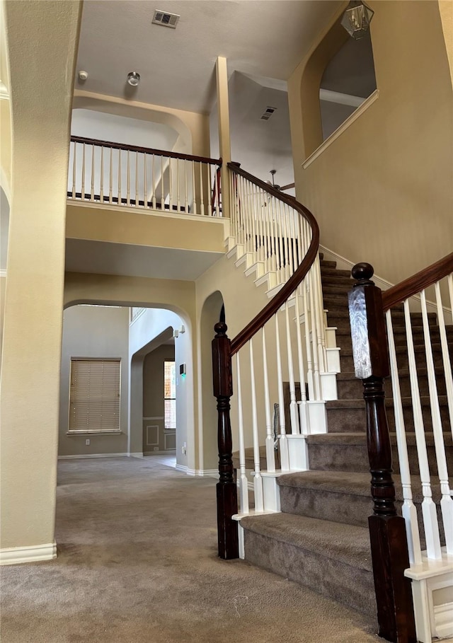 1435 Delta Dr, Cedar Hill, TX 75104 - stairway with arched walkways, a towering ceiling, carpet floors, and baseboards