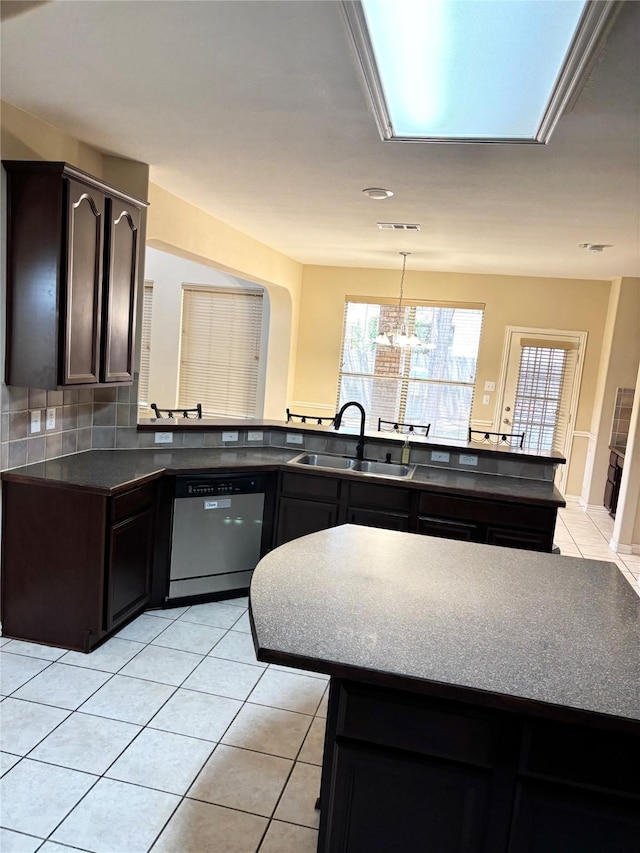 1435 Delta Dr, Cedar Hill, TX 75104 - kitchen featuring a sink, stainless steel dishwasher, light tile patterned flooring, dark countertops, and a peninsula