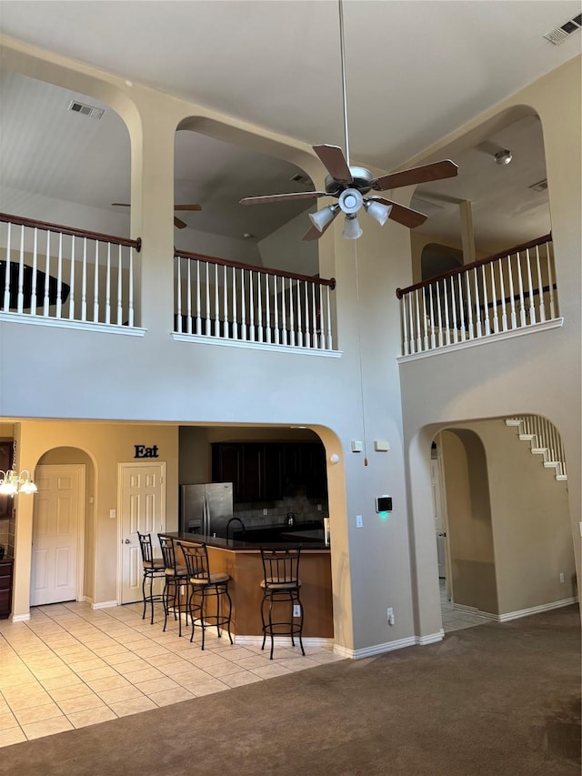 1435 Delta Dr, Cedar Hill, TX 75104 - living area with a towering ceiling, a ceiling fan, light tile patterned floors, light colored carpet, and arched walkways
