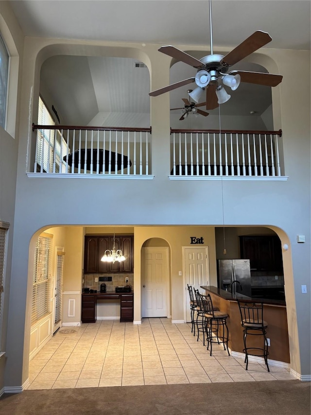 1435 Delta Dr, Cedar Hill, TX 75104 - kitchen featuring stainless steel fridge with ice dispenser, a towering ceiling, a ceiling fan, light tile patterned floors, and arched walkways