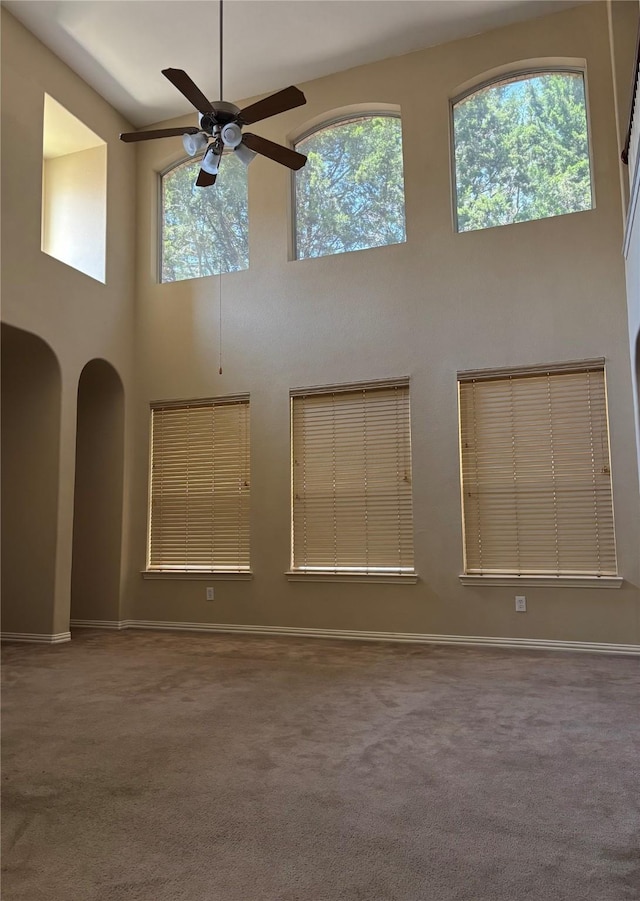 1435 Delta Dr, Cedar Hill, TX 75104 - empty room with a towering ceiling, a ceiling fan, carpet floors, arched walkways, and baseboards