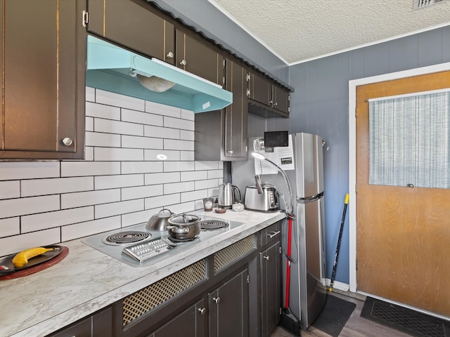 kitchen featuring under cabinet range hood, backsplash, appliances with stainless steel finishes, a textured ceiling, and light countertops