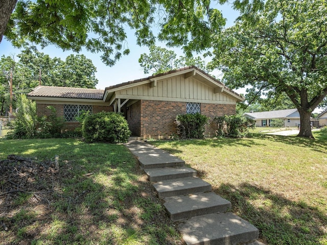 ranch-style house featuring brick siding, a tiled roof, and a front yard