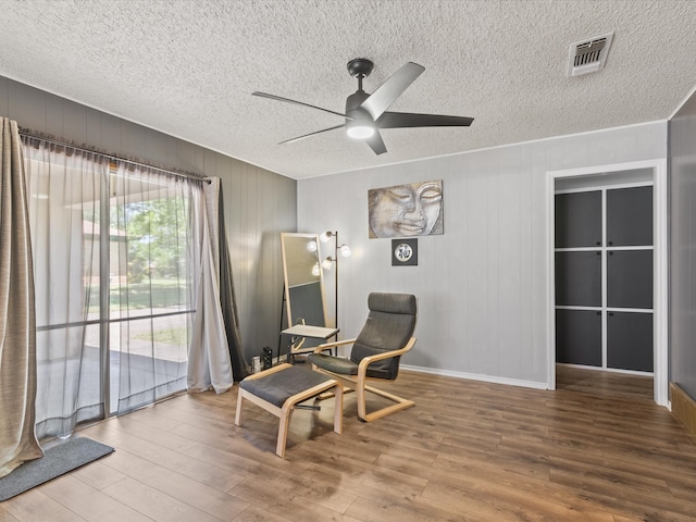 sitting room with a ceiling fan, wood finished floors, and a textured ceiling