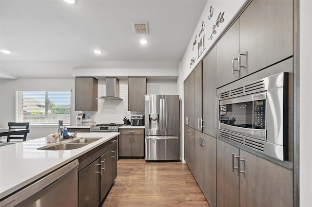 3812 Wheatland Trl, Forney, TX 75126 - kitchen with stainless steel appliances, wall chimney range hood, a sink, light countertops, and light wood finished floors
