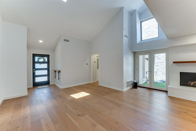 3326 Courtyard Pl, Farmers Branch, TX 75234 - unfurnished living room featuring high vaulted ceiling, light wood-style floors, a brick fireplace, and baseboards