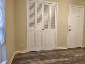 5728 Rockhill Rd, Fort Worth, TX 76112 - unfurnished bedroom featuring a closet, baseboards, and dark wood finished floors