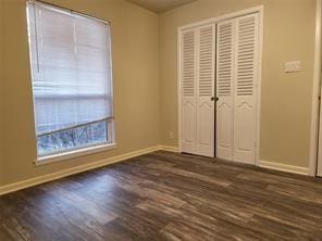 5728 Rockhill Rd, Fort Worth, TX 76112 - unfurnished bedroom featuring baseboards, dark wood-style floors, and a closet