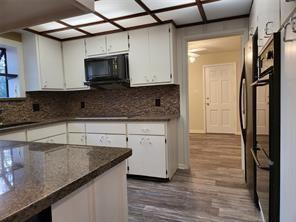 5728 Rockhill Rd, Fort Worth, TX 76112 - kitchen featuring black microwave, white cabinets, and backsplash