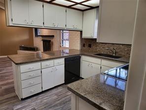 5728 Rockhill Rd, Fort Worth, TX 76112 - kitchen with dishwasher, a peninsula, decorative backsplash, dark wood-style floors, and a fireplace