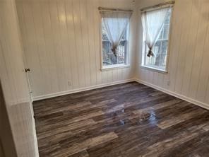 5728 Rockhill Rd, Fort Worth, TX 76112 - unfurnished room with dark wood-style flooring and wood walls