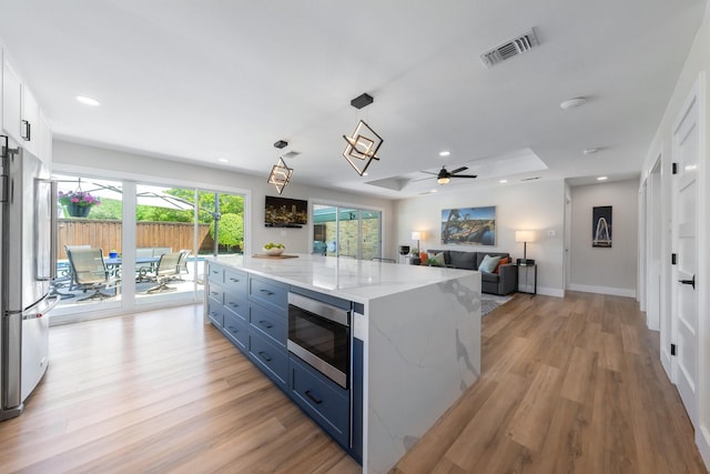 15732 Nedra Way, Dallas, TX 75248 - kitchen with appliances with stainless steel finishes, ceiling fan, light wood-style flooring, blue cabinetry, and light stone counters
