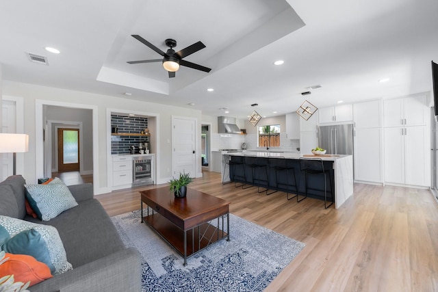 15732 Nedra Way, Dallas, TX 75248 - living room with beverage cooler, a tray ceiling, ceiling fan, recessed lighting, and light wood-style flooring