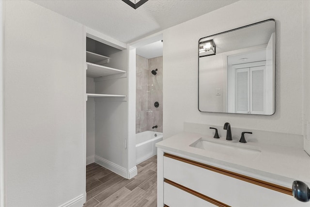 11230 Cotillion Dr, Dallas, TX 75228 - full bath with vanity, wood finished floors, baseboards,  shower combination, and a textured ceiling