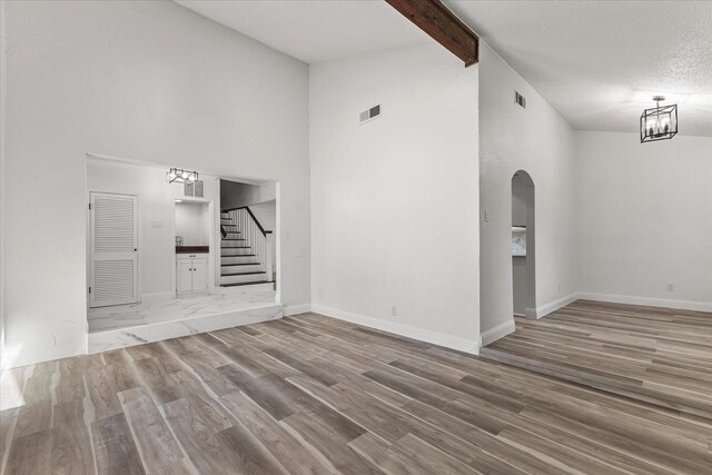 11230 Cotillion Dr, Dallas, TX 75228 - unfurnished living room with a chandelier, stairway, wood finished floors, high vaulted ceiling, and arched walkways