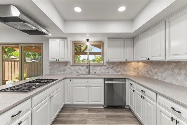 11230 Cotillion Dr, Dallas, TX 75228 - kitchen with stainless steel appliances, a sink, wall chimney range hood, white cabinets, and backsplash