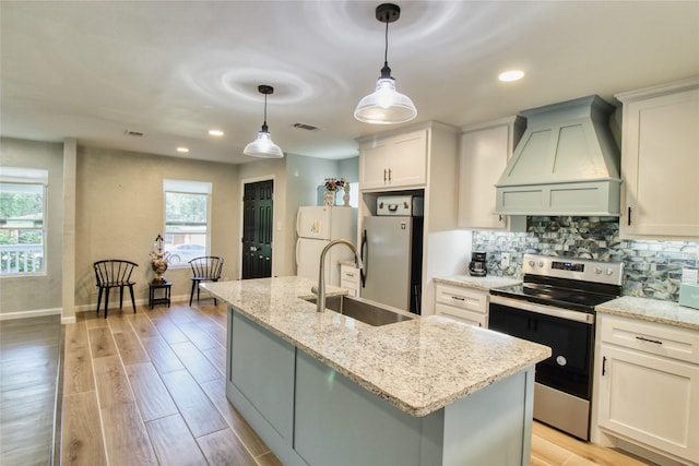 505 E 4th St, Weatherford, TX 76086 - kitchen featuring stainless steel appliances, custom range hood, tasteful backsplash, a kitchen island with sink, and pendant lighting