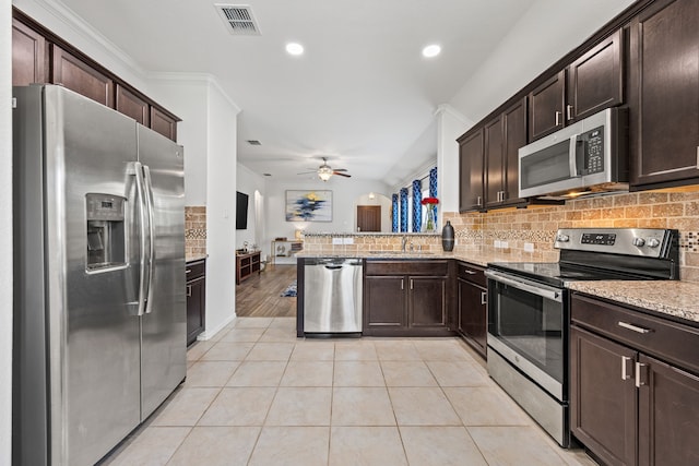 3010 Rosemount Ln, Forney, TX 75126 - kitchen with stainless steel appliances, backsplash, dark brown cabinetry, light stone countertops, and ceiling fan