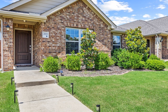 3010 Rosemount Ln, Forney, TX 75126 - view of exterior entry featuring brick siding, a yard, and roof with shingles