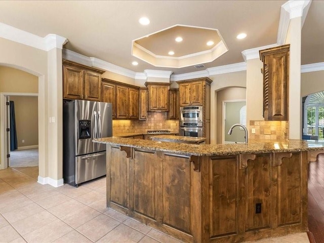 113 Winding Creek Ln, Waco, TX 76657 - kitchen with appliances with stainless steel finishes, arched walkways, ornamental molding, stone counters, and a kitchen breakfast bar