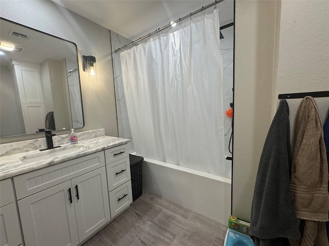 bathroom with shower / bath combo with shower curtain, vanity, and a textured wall
