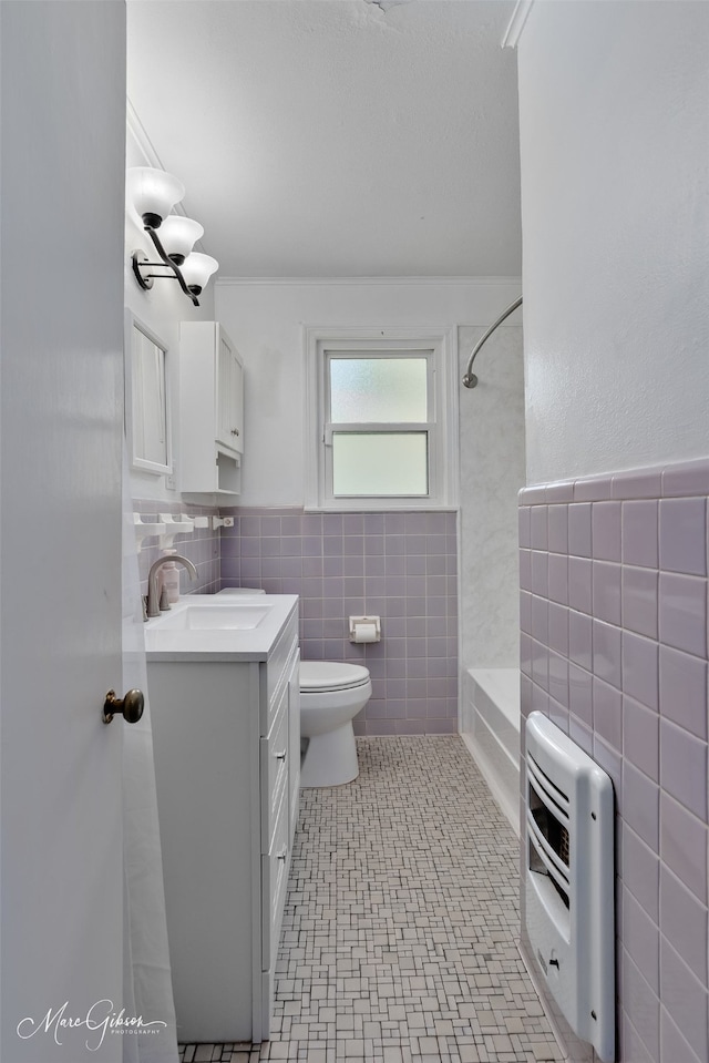 full bath featuring tile walls, heating unit, vanity, toilet, and shower / washtub combination