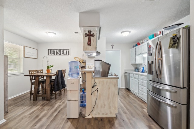816 Red Oak Ct, Azle, TX 76020 - kitchen featuring stainless steel appliances, light wood finished floors, light countertops, a textured ceiling, and a sink