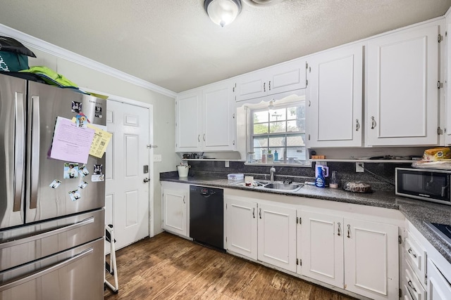 kitchen with freestanding refrigerator, black dishwasher, a sink, dark countertops, and ornamental molding