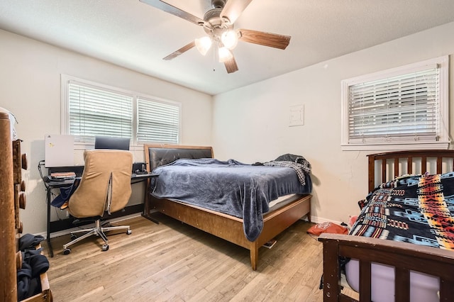 bedroom with light wood-type flooring, a ceiling fan, and baseboards