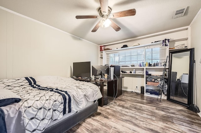 bedroom featuring crown molding, wood finished floors, vaulted ceiling, a textured ceiling, and a ceiling fan