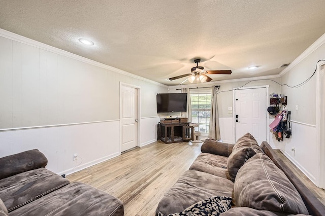 living area featuring a textured ceiling, wood finished floors, crown molding, a ceiling fan, and baseboards