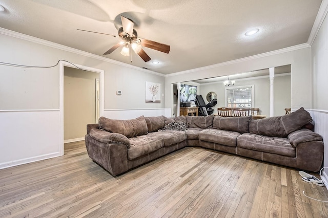 living room with light wood-style floors, crown molding, a ceiling fan, and a chandelier
