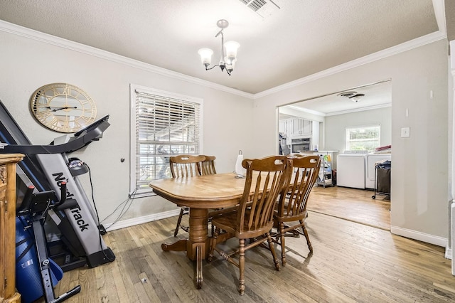 dining room with washer and clothes dryer, light wood-style flooring, a chandelier, ornamental molding, and a textured ceiling