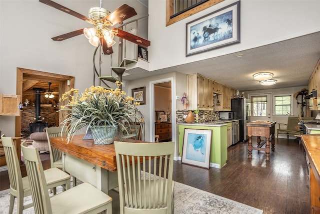 1867 Chaparral Dr, Gainesville, TX 76240 - dining area with ceiling fan, a wood stove, a towering ceiling, and dark wood-style flooring