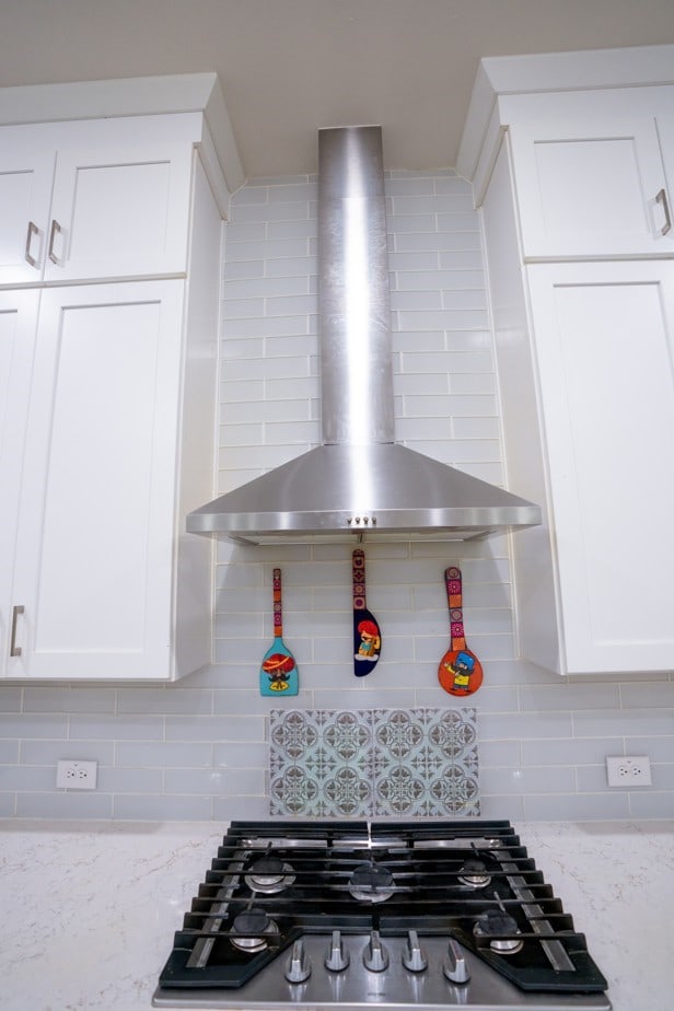 4569 Wilbarger St, Plano, TX 75024 - kitchen view of wall chimney range hood, tasteful backsplash, white cabinetry, stainless steel gas cooktop, and light stone counters