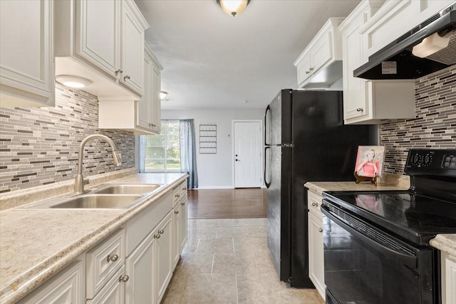 kitchen with under cabinet range hood, black electric range oven, a sink, light countertops, and decorative backsplash