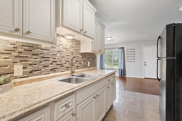 kitchen featuring freestanding refrigerator, a sink, light countertops, and decorative backsplash