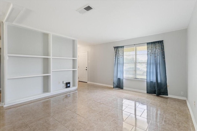 empty room featuring tile patterned floors, baseboards, and built in features