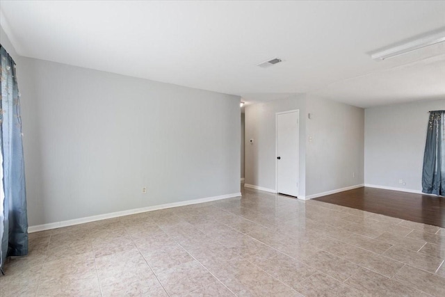 tiled empty room featuring baseboards