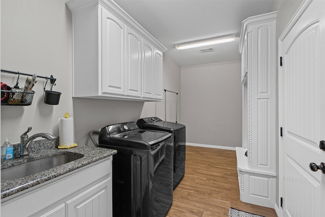 3407 Holbrook Rd, Springtown, TX 76082 - laundry room featuring independent washer and dryer, light wood-type flooring, and cabinet space