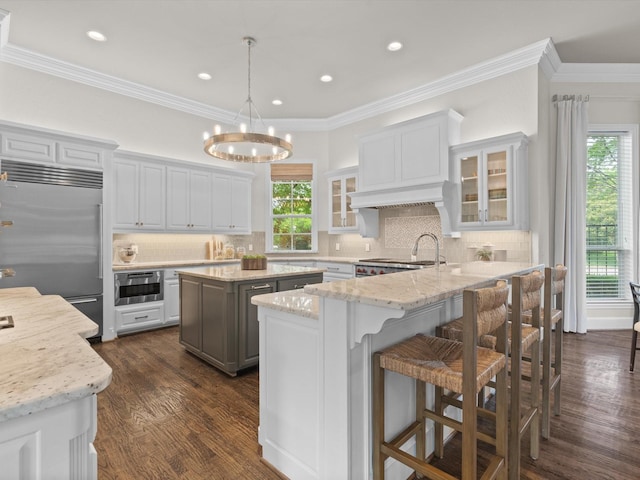 5916 Orchard Park Dr, Frisco, TX 75034 - kitchen with appliances with stainless steel finishes, glass insert cabinets, a center island, dark wood finished floors, and tasteful backsplash
