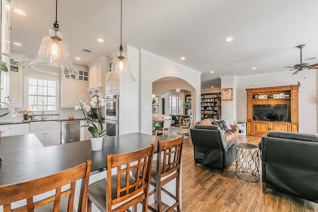 1132 Mount Ln, Rhome, TX 76078 - dining space featuring arched walkways, light wood finished floors, ornamental molding, a ceiling fan, and plenty of natural light