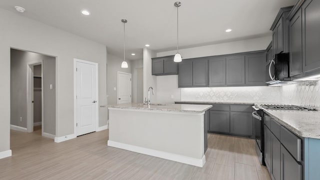 1900 Stetson St, Northlake, TX 76247 - kitchen featuring gas range, a sink, decorative backsplash, light stone counters, and a kitchen island with sink