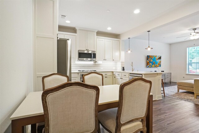 7132 Huckleberry Dr, Mckinney, TX 75070 - kitchen with appliances with stainless steel finishes, a peninsula, backsplash, a ceiling fan, and dark wood finished floors