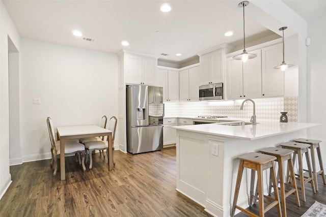 7132 Huckleberry Dr, Mckinney, TX 75070 - kitchen featuring stainless steel appliances, a peninsula, a sink, white cabinetry, and tasteful backsplash